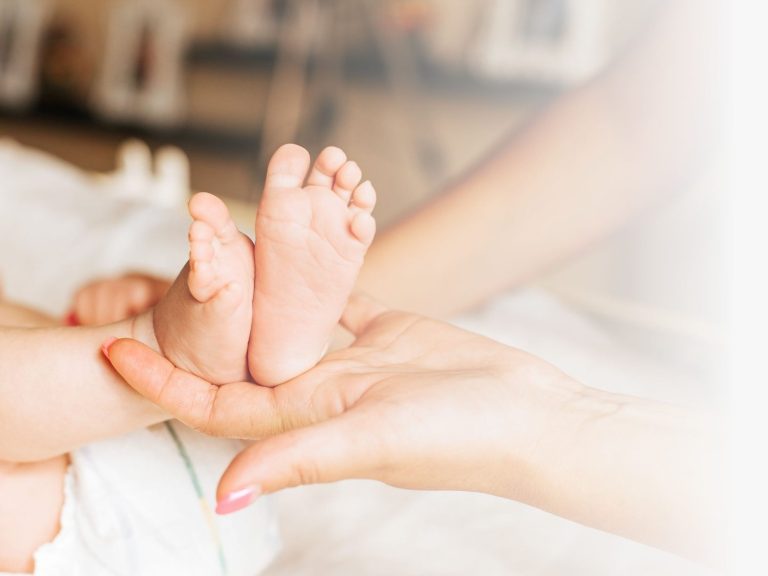 A mother holds her newborn in water, with a supportive partner beside her.
