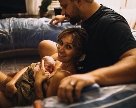 A pregnant woman leans on an exercise ball while a physical therapist demonstrates a pelvic floor exercise.